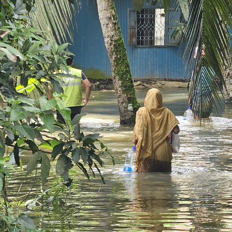 A woman receives essential supplies of clean water, ORS, and dry food provided by Oxfam in the aftermath of the 2024 Bangladesh floods.