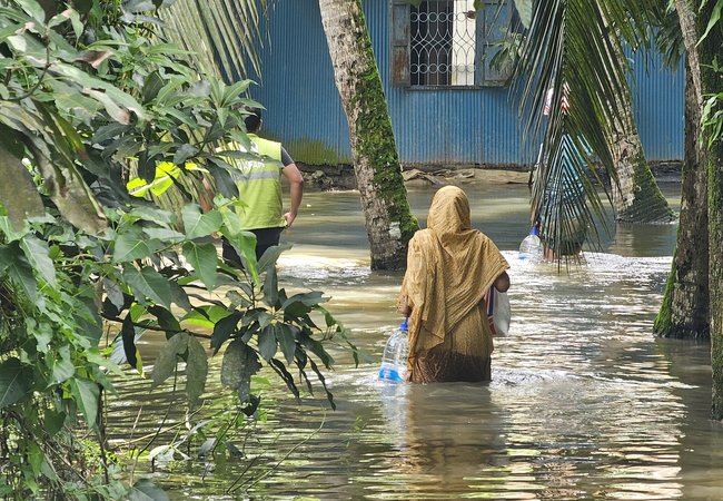 A woman receives essential supplies of clean water, ORS, and dry food provided by Oxfam in the aftermath of the 2024 Bangladesh floods.