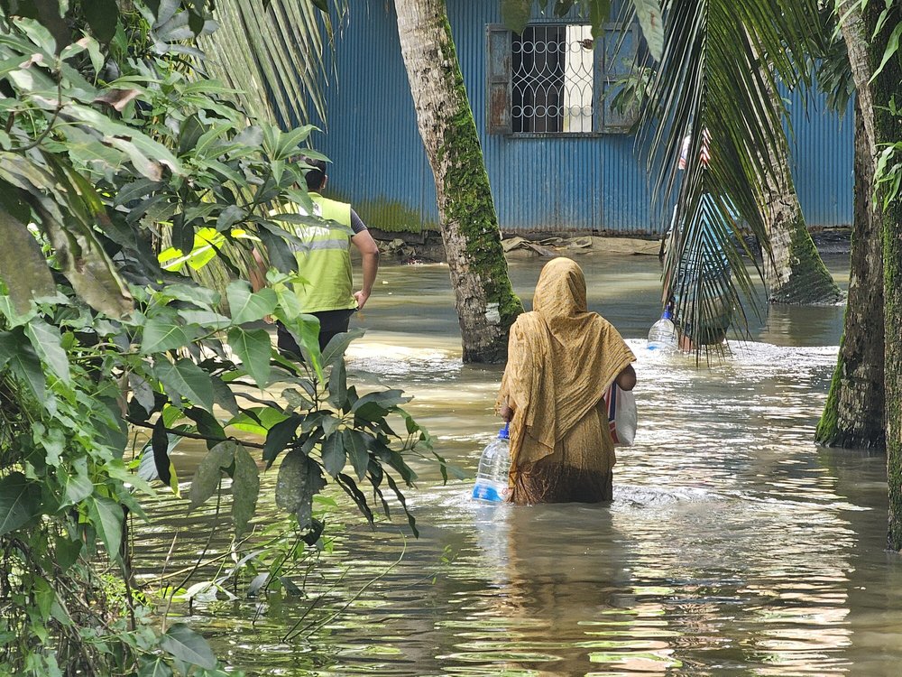 A woman receives essential supplies of clean water, ORS, and dry food provided by Oxfam in the aftermath of the 2024 Bangladesh floods.