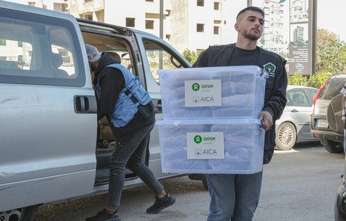 A young man unloads Oxfam-branded emergency food packages from a van in Tripoli, Lebanon.