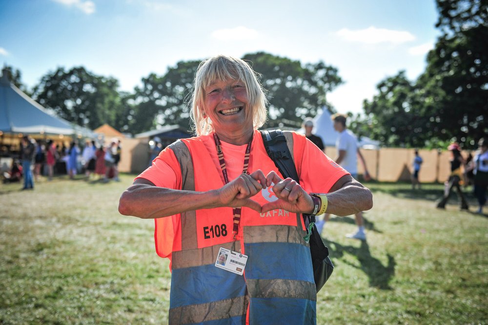 Oxfam steward smiling and making a heart symbol with her hands