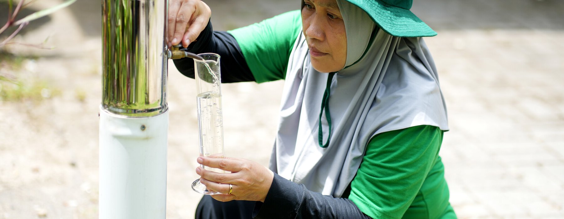 Mariani using an ombrometer to check water levels in her village in Dasan Geria, Indonesia.