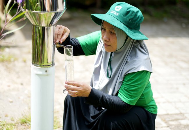 Mariani using an ombrometer to check water levels in her village in Dasan Geria, Indonesia.