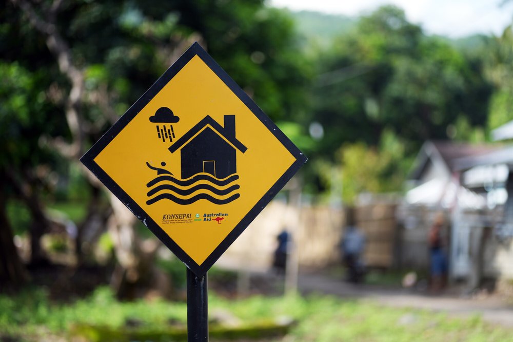 A yellow diamond-shaped hazard sign featuring a graphic depicting floods