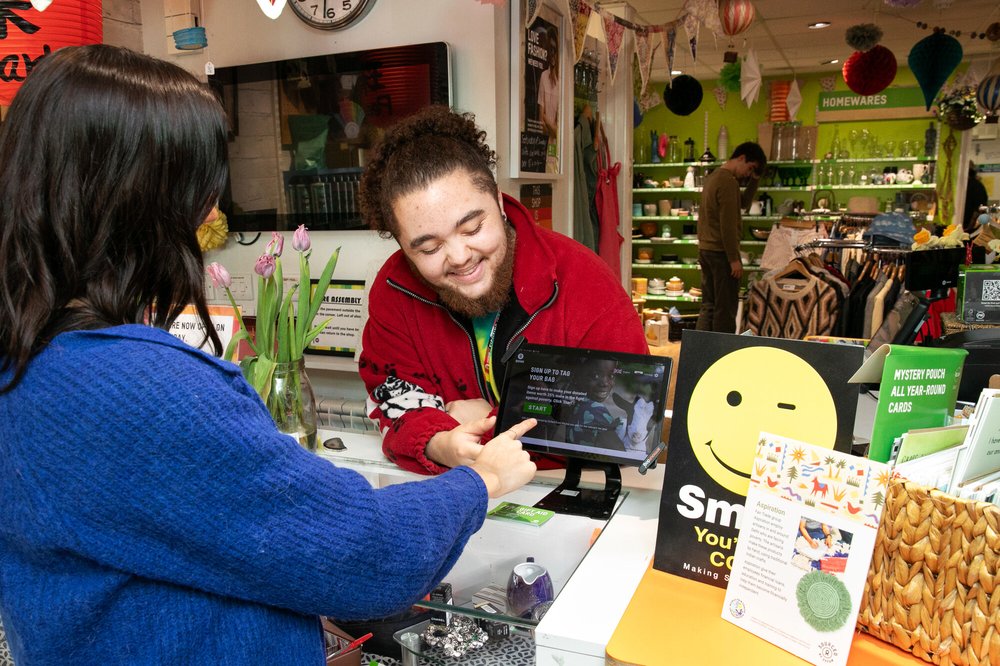 An image of an Oxfam volunteer helping a customer sign up to Gift Aid