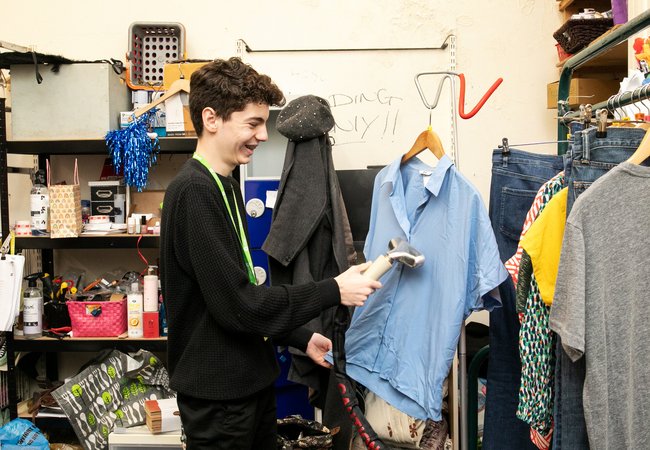 A man smiling as he steams clothes