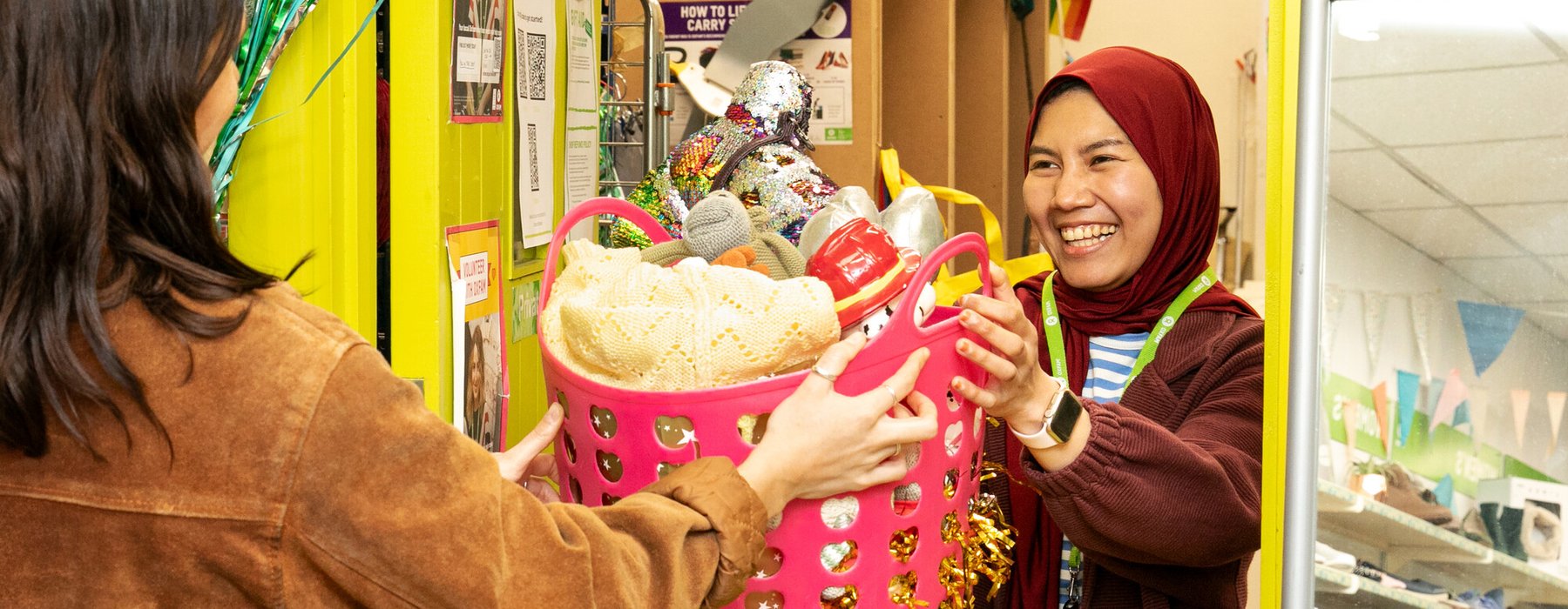 An image of donations being handed to an Oxfam member of staff in an Oxfam high street shop