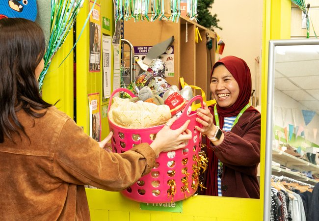 An image of donations being handed to an Oxfam member of staff in an Oxfam high street shop