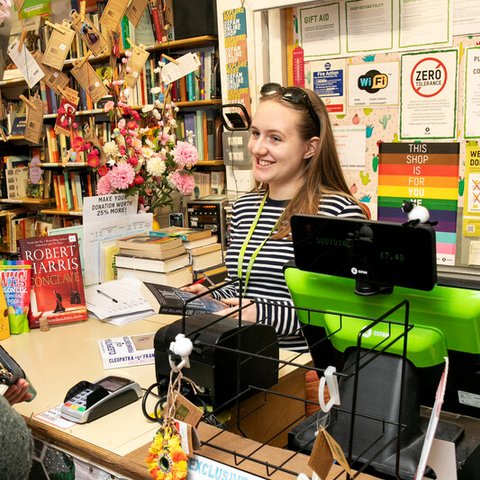 A woman smiling standing at the till