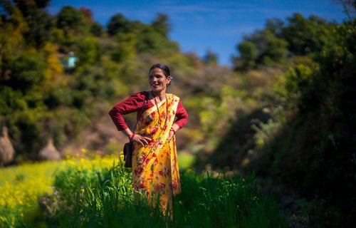 A woman standing in a field smiling, with her hands on her hips.