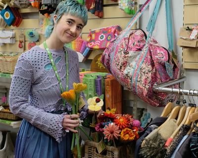 Han, a volunteer in Oxfam's shop in Skipton, arranges some woven flowers in a basket.