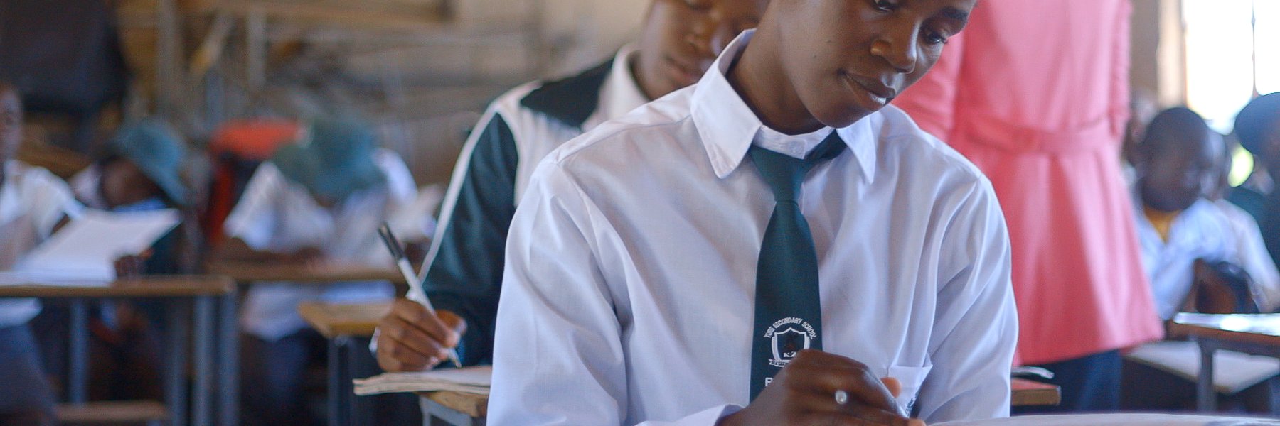 Children in white shirts with green ties in a classroom in Zimbabwe.