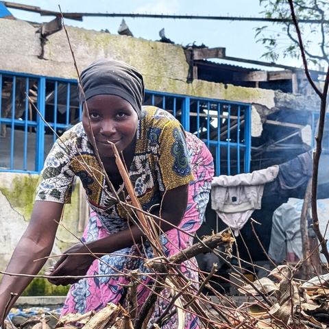 Muhawe Myriam Charmante is smiling and looking at the camera while collecting firewood at the collective gathering site in Sake, DRC