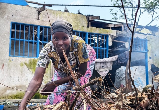 Muhawe Myriam Charmante is smiling and looking at the camera while collecting firewood at the collective gathering site in Sake, DRC