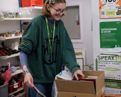 A woman smiling and looking into a box of donations