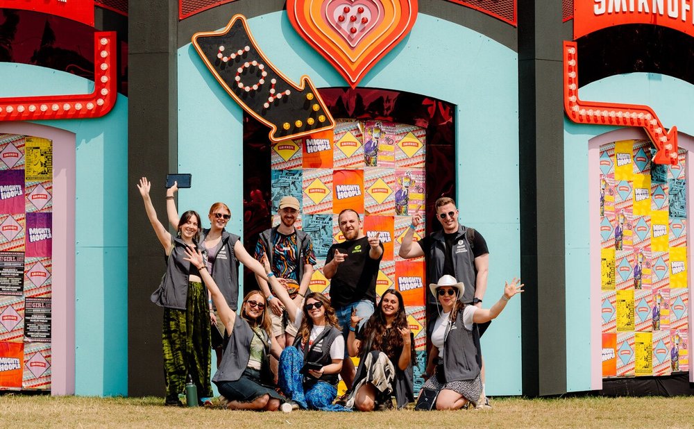 Group of smiling Oxfam Festival campaigners under a joy sign