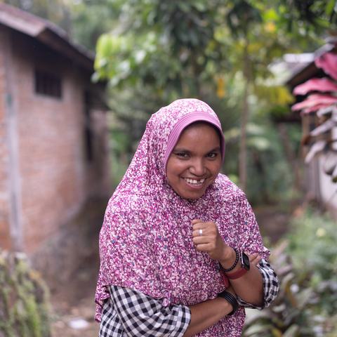Salbia, a smiling woman with a pink head-scarf poses for a photo.