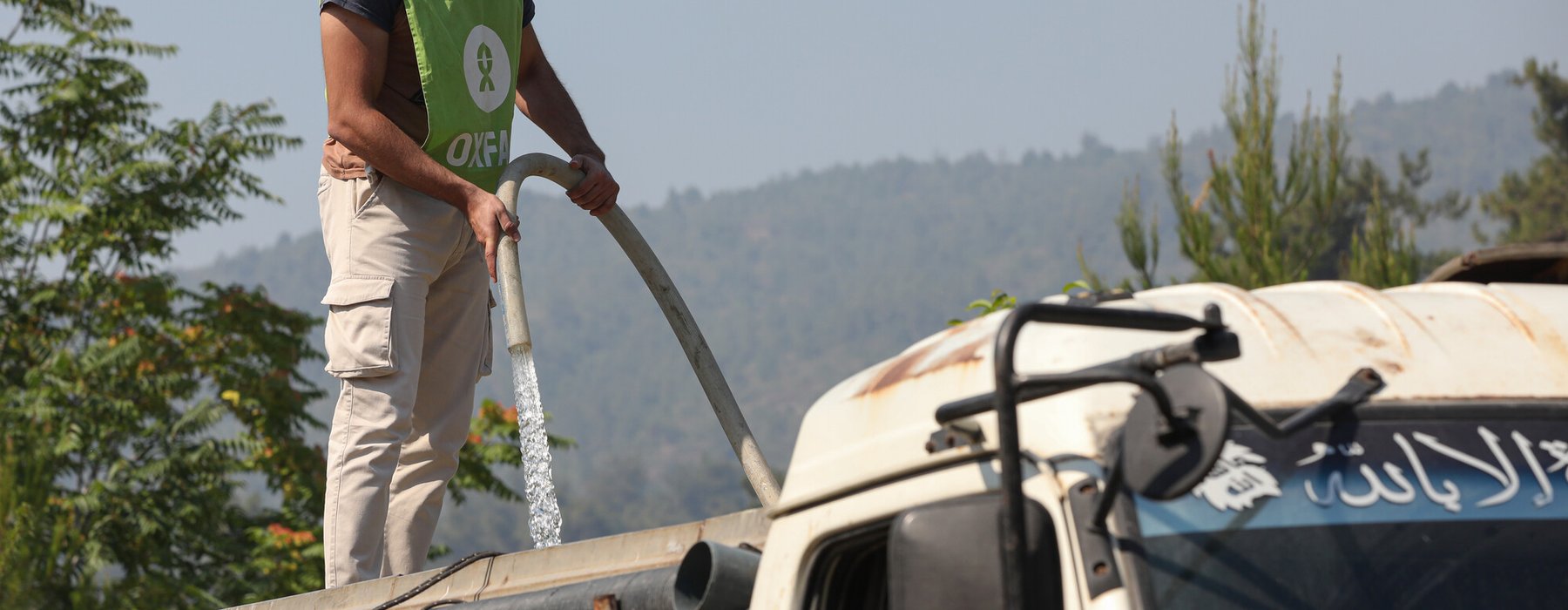 An Oxfam staff member refills a water tanker in Ballouran, rural Latakia, Syrian Arab Republic.