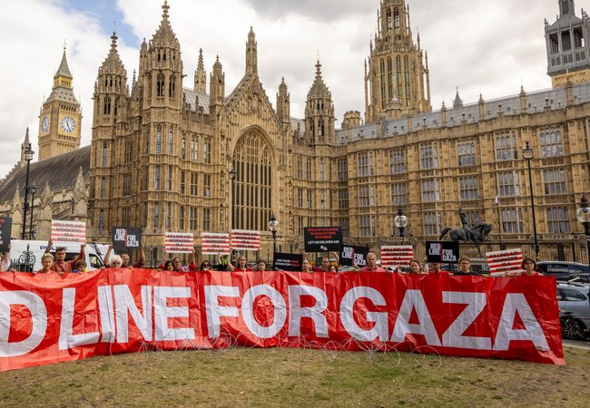 Protest outside of Westminster - a line of people holding a banner that says Red Line for Gaza