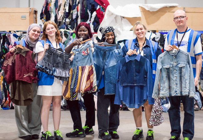 Upcycling students from Leeds Beckett university pose with their upcycled clothes at Oxfam's Batley warehouse.