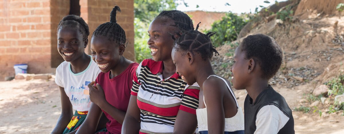 Angela is sitting with her four daughters outside their home in Namwala, Southern Province, Zambia