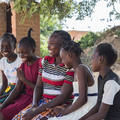 Angela is sitting with her four daughters outside their home in Namwala, Southern Province, Zambia
