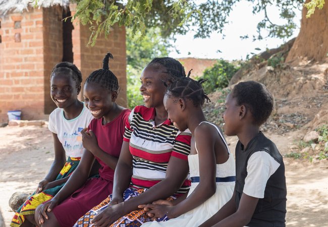 Angela is sitting with her four daughters outside their home in Namwala, Southern Province, Zambia