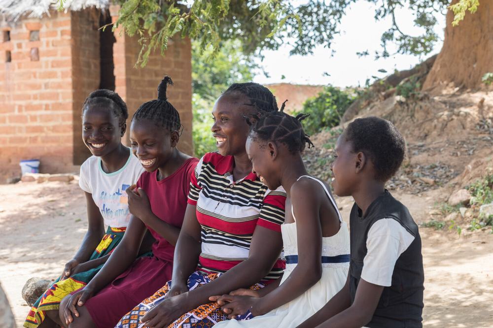 Angela is sitting with her four daughters outside their home in Namwala, Southern Province, Zambia