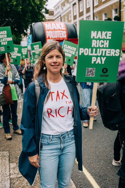 Tamsyn and Oxfam suppoter is holding 'Make Rich Polluters Pay' placard