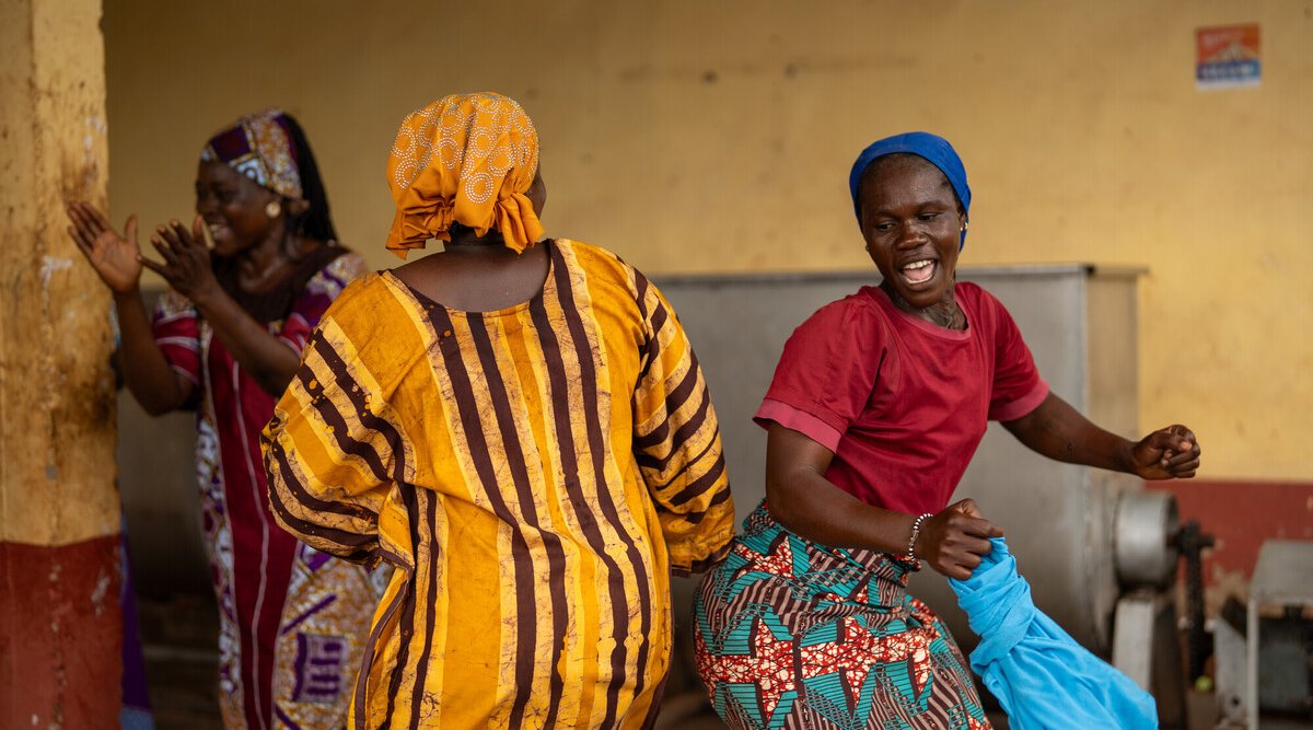 Sadiya and Asia wearing bright clothes dancing together in a stone courtyard