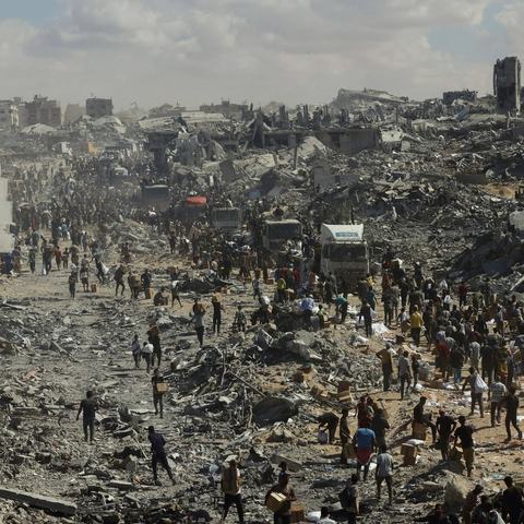 People walk through a heavily damaged street in Khan Younis, southern Gaza Strip, on October 12, 2025.