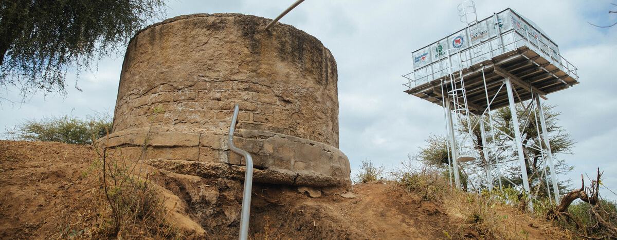 Cement and steel water tanks on top of a dry muddy hill in Uran, Marsabit County, Kenya.