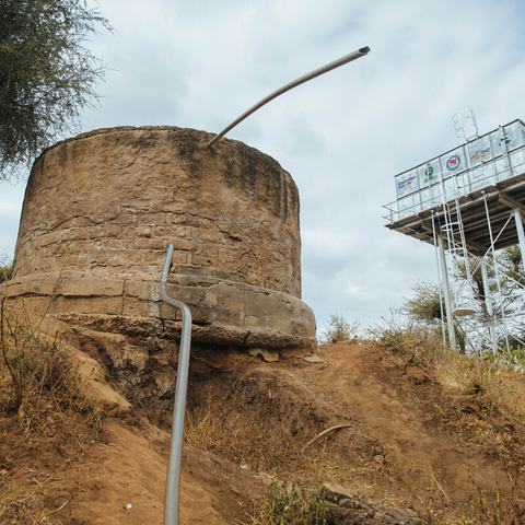 Cement and steel water tanks on top of a dry muddy hill in Uran, Marsabit County, Kenya.
