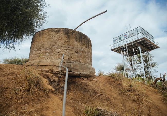Cement and steel water tanks on top of a dry muddy hill in Uran, Marsabit County, Kenya.