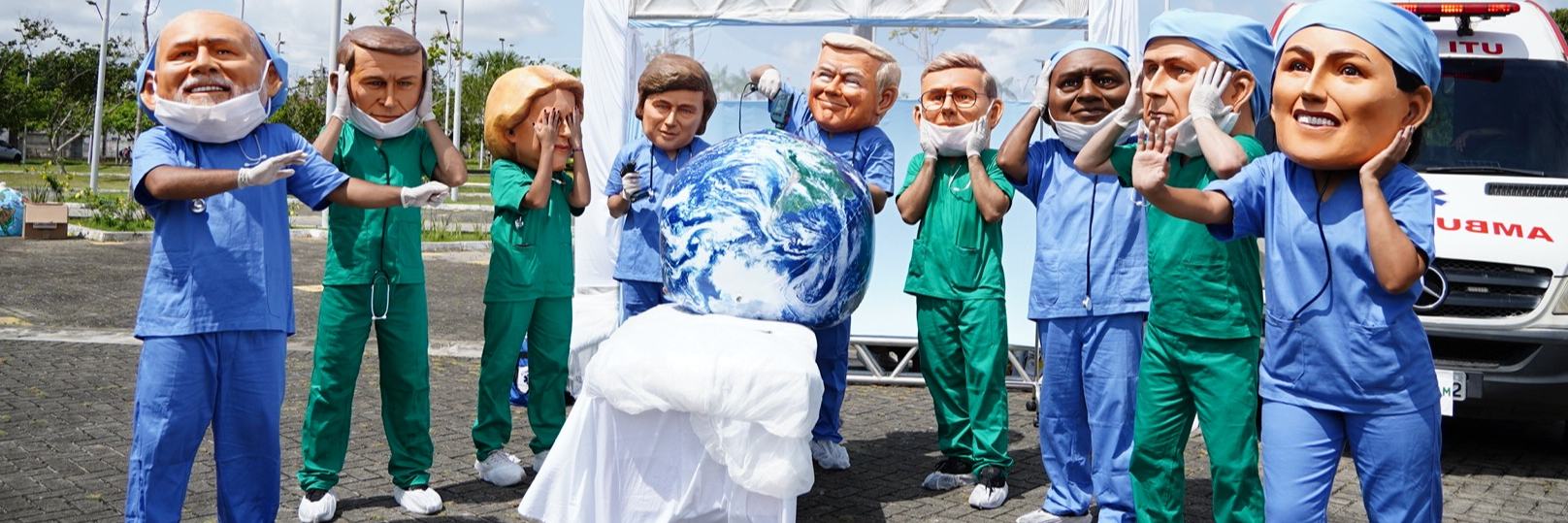 Activists dressed up in big heads that represent world leaders - all dressed as surgeons doing poor surgery on the planet.