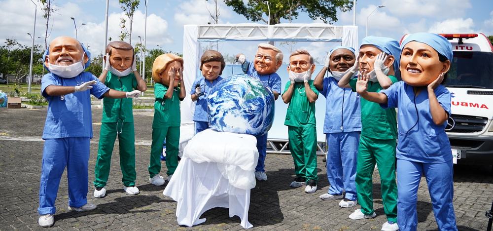 Activists dressed up in big heads that represent world leaders - all dressed as surgeons doing poor surgery on the planet.