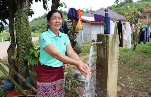 Vilay (age 39) washes her hands at the newly installed water tap in front of her own house in Namyon Village, Lao People's Democratic Republic.