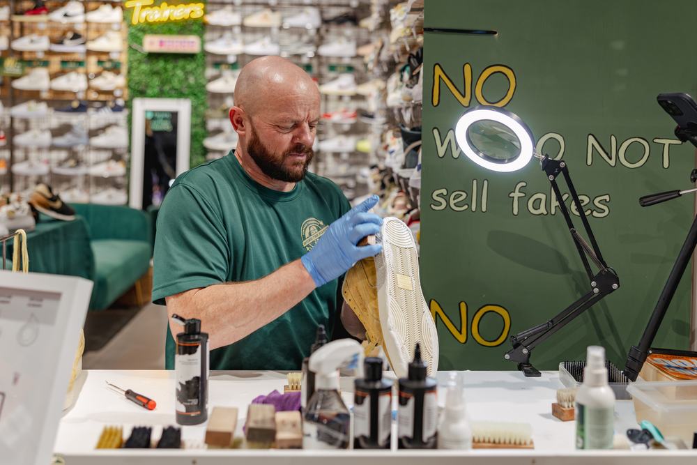 Man sits at desk cleaning white trainer sole