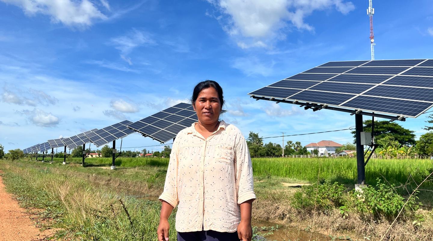 a woman stands in front of a row of solar panels.