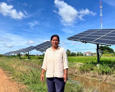 a woman stands in front of a row of solar panels.
