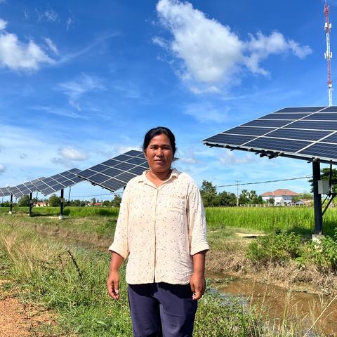 a woman stands in front of a row of solar panels.