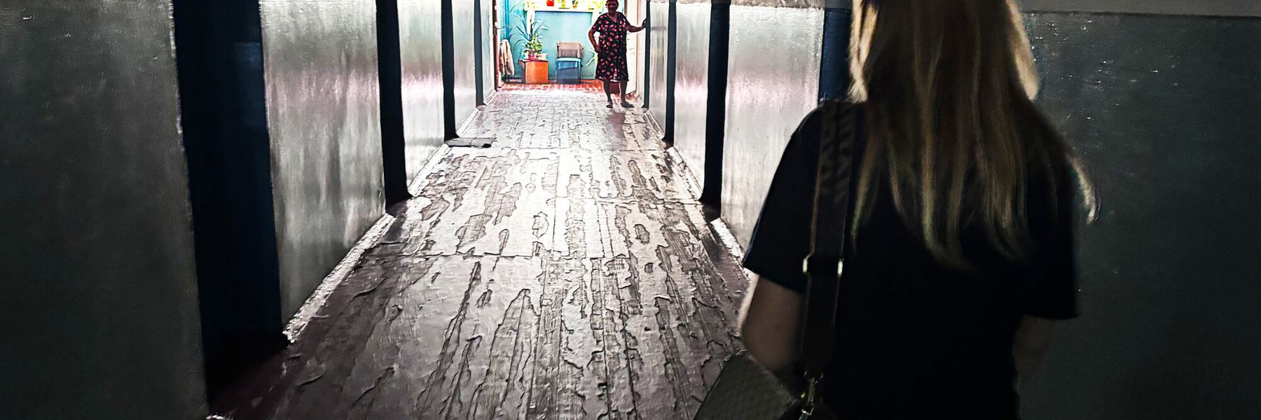 A woman walks down a dark hallways.