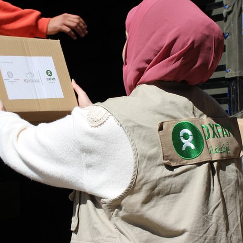 A female Oxfam colleague in the south of Beirut unloading a box of hygiene kits and menstrual health management kits ready to distribute to displaced people.