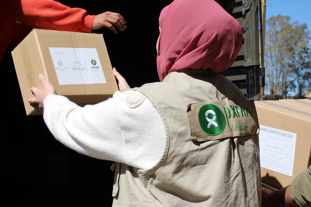 A female Oxfam colleague in the south of Beirut unloading a box of hygiene kits and menstrual health management kits ready to distribute to displaced people.