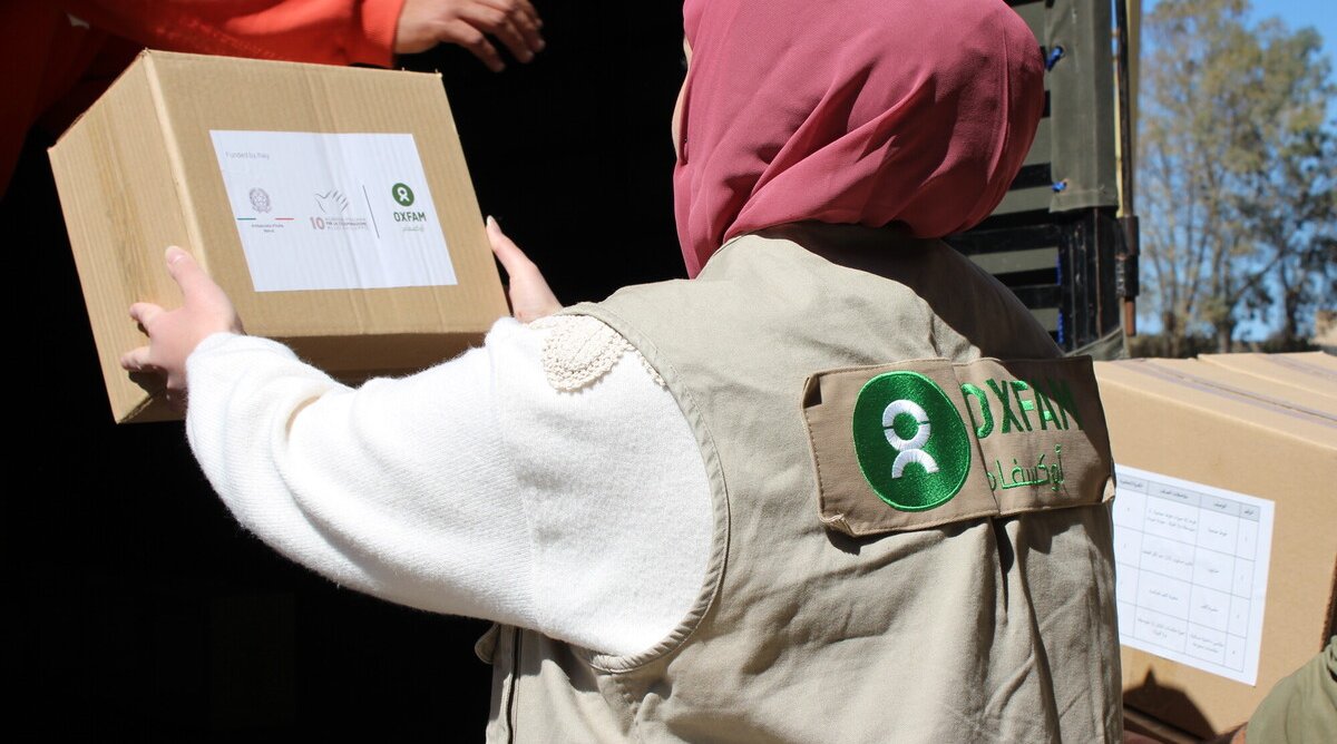 A female Oxfam colleague in the south of Beirut unloading a box of hygiene kits and menstrual health management kits ready to distribute to displaced people.