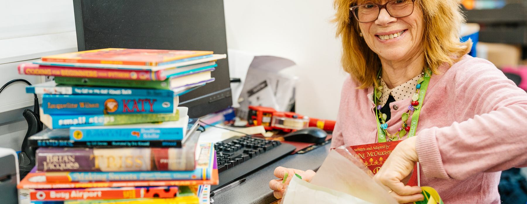 Volunteer Harriet pricing up childrens books at Oxfam Shop Magdalen Street, Norwich