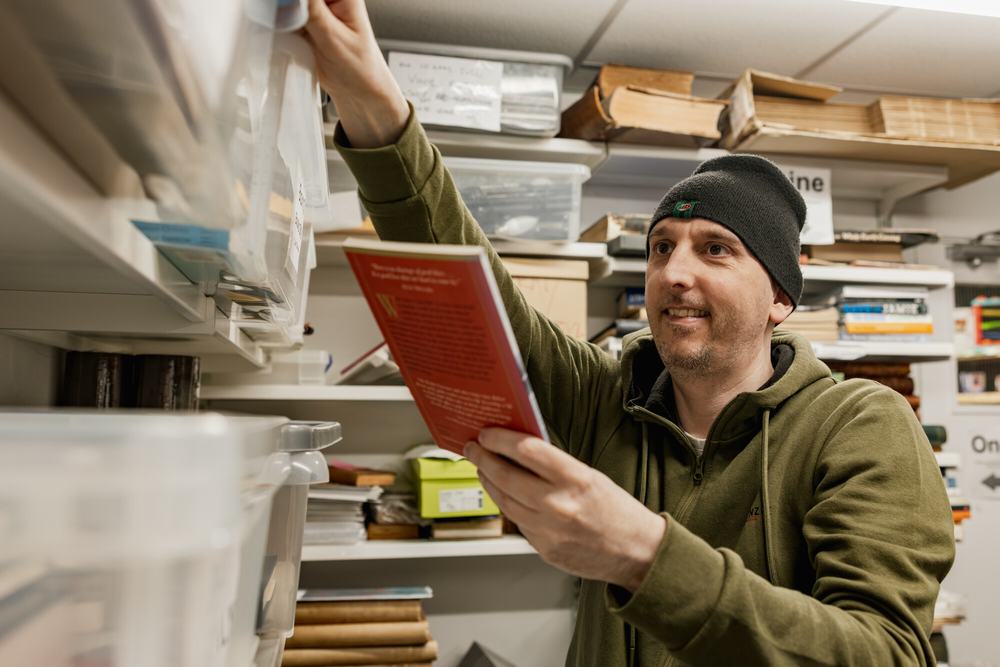 Volunteer Dan, sorting books for listing in the online shop, in the backroom of Didsbury shop, Manchester.