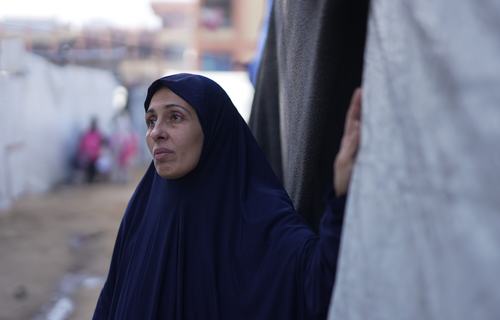 Rania stands in front of her tent in a makeshift tent camp in Gaza City.