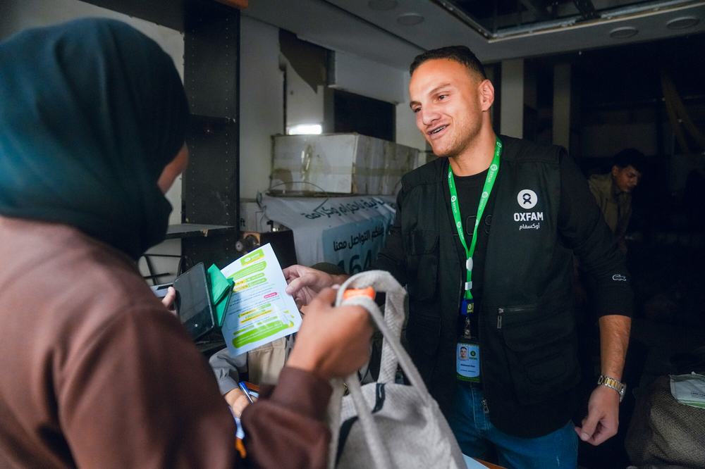 Oxfam staff member shares a dignity kit with someone