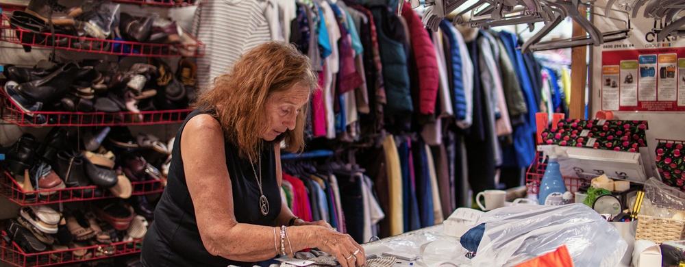 Barbara leaning over a table sorting donations